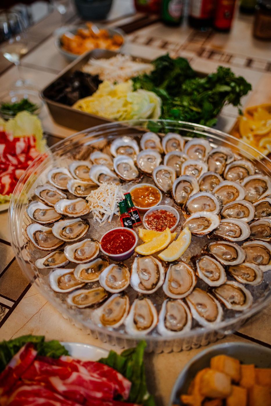 A large round platter of freshly shucked oysters with sauces and lemon