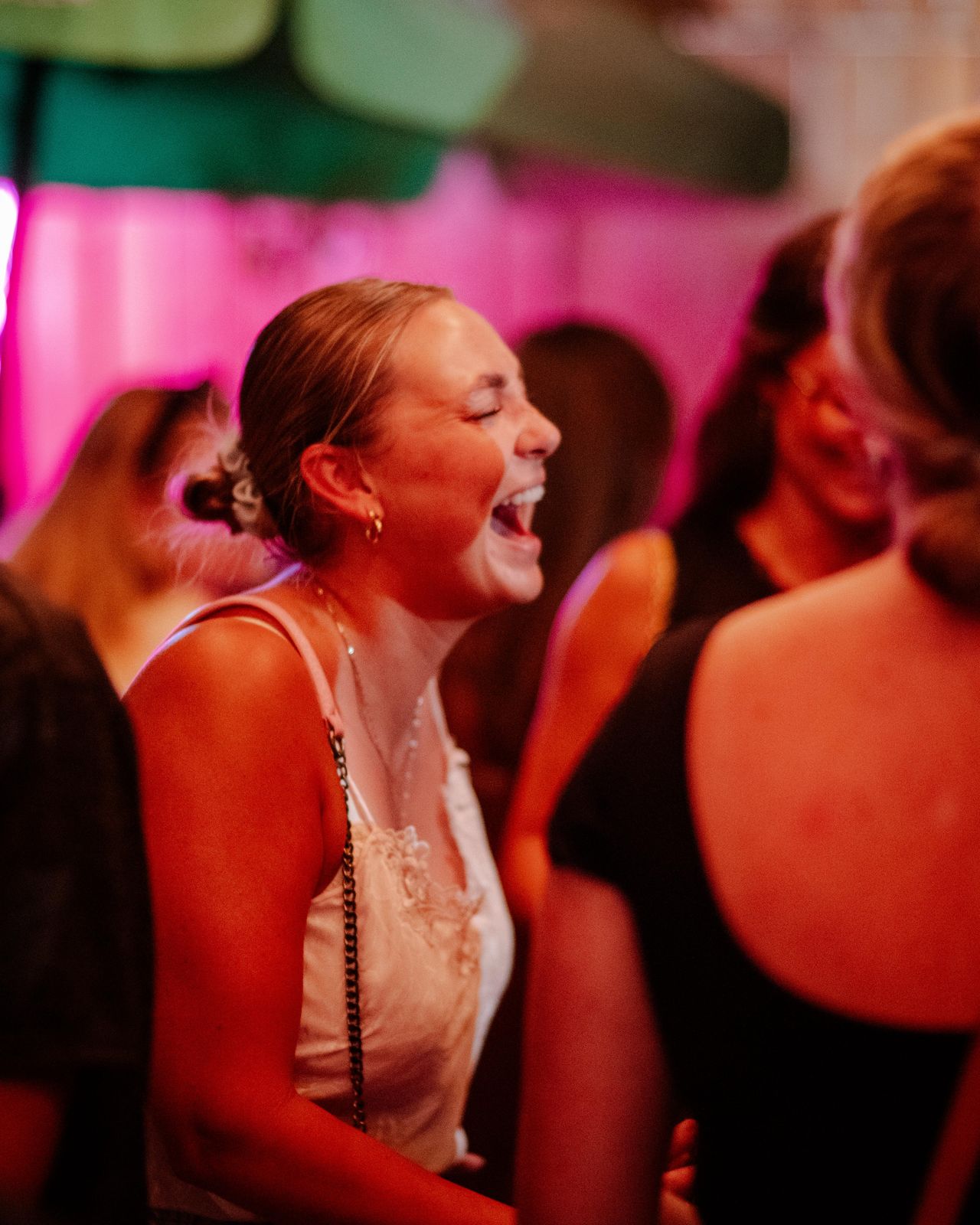 A guest laughing in pink light at Art Crawl