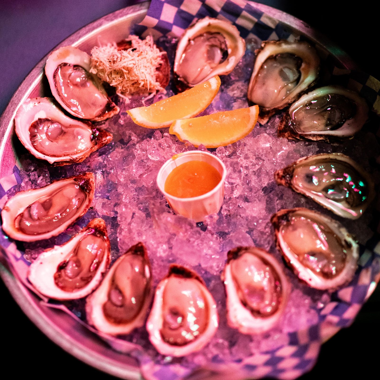 A round oyster platter glowing in pink light at Art Crawl