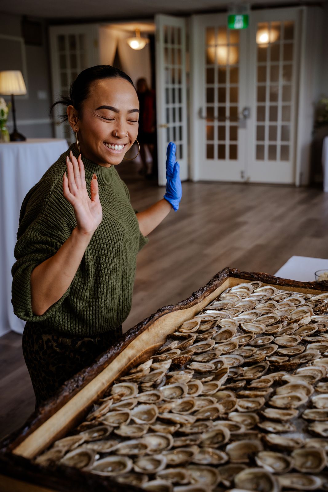 A shucker waving beside a huge tray of shucked oysters
