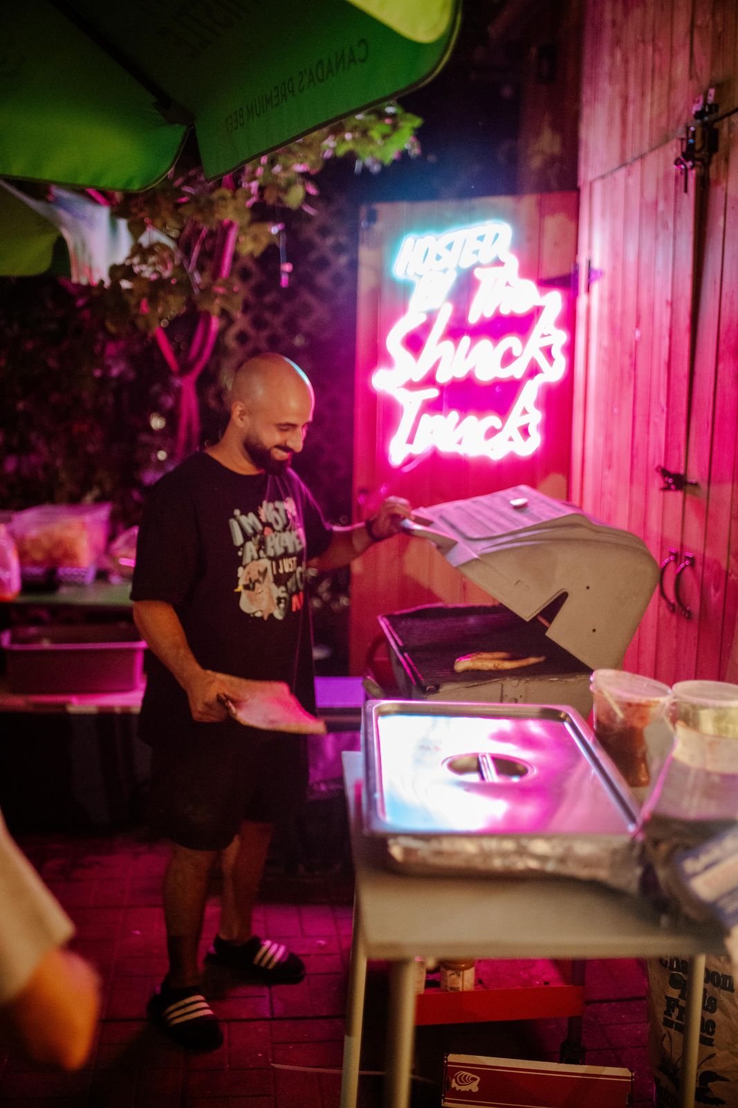 Shucking oysters under the pink neon sign