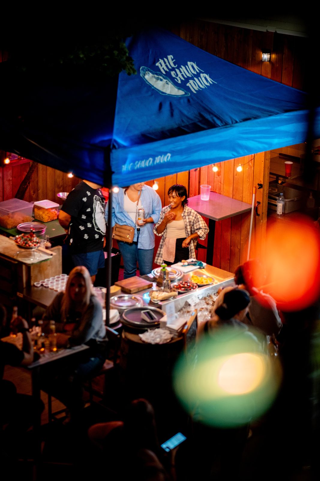 The blue Shuck Truck tent glowing at night during Supercrawl