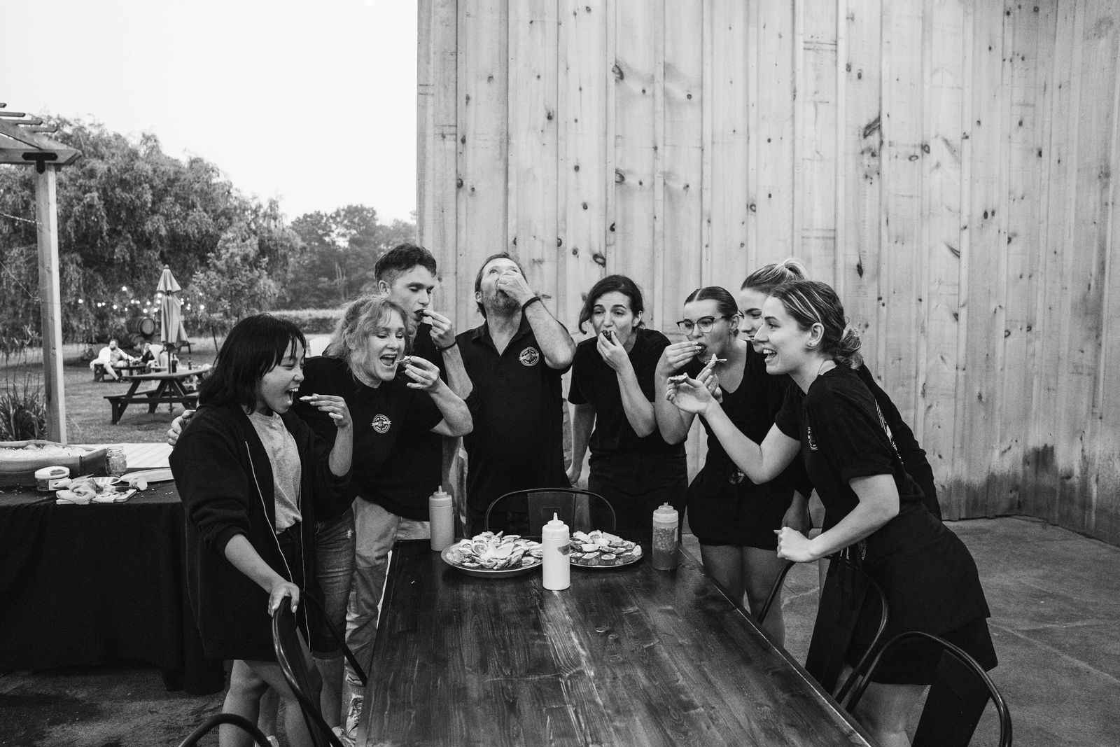 The team toasting with oysters, in black and white