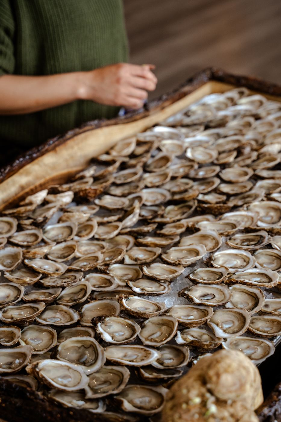 Close up of oysters covering the live-edge wooden board