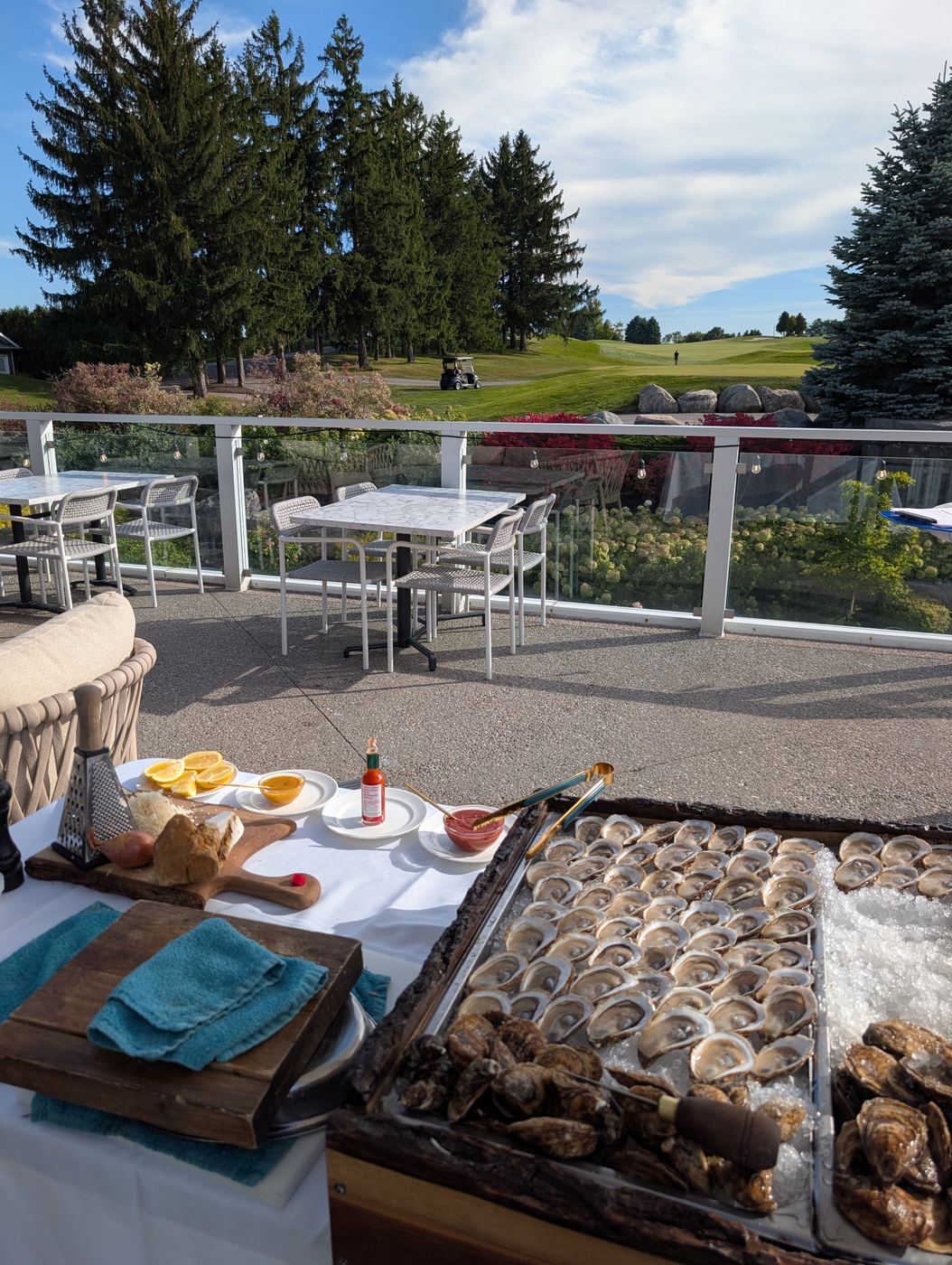 The live-edge oyster board set up on a golf club patio overlooking the course