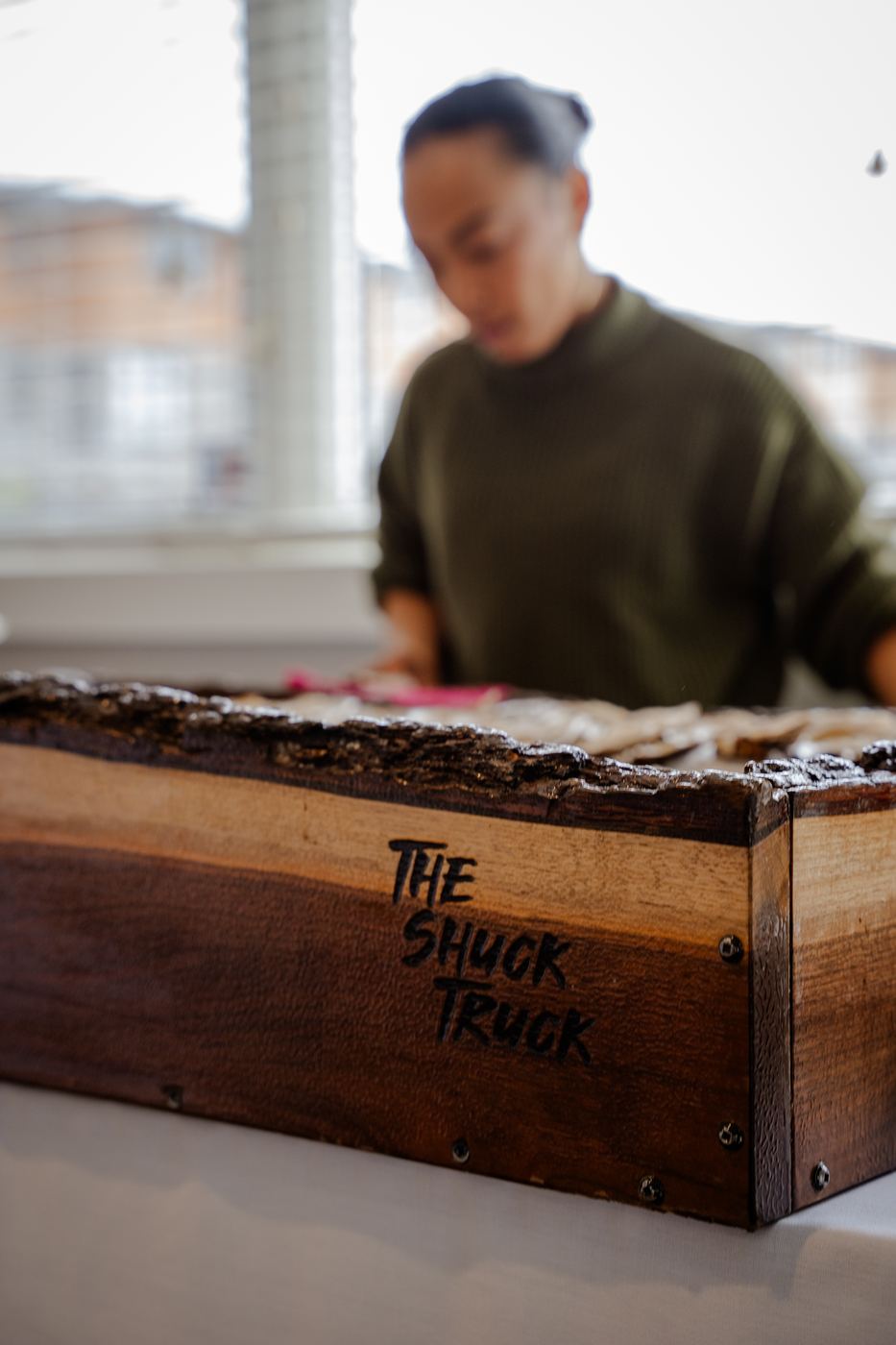 The end of the live-edge board with The Shuck Truck hand-lettered on it