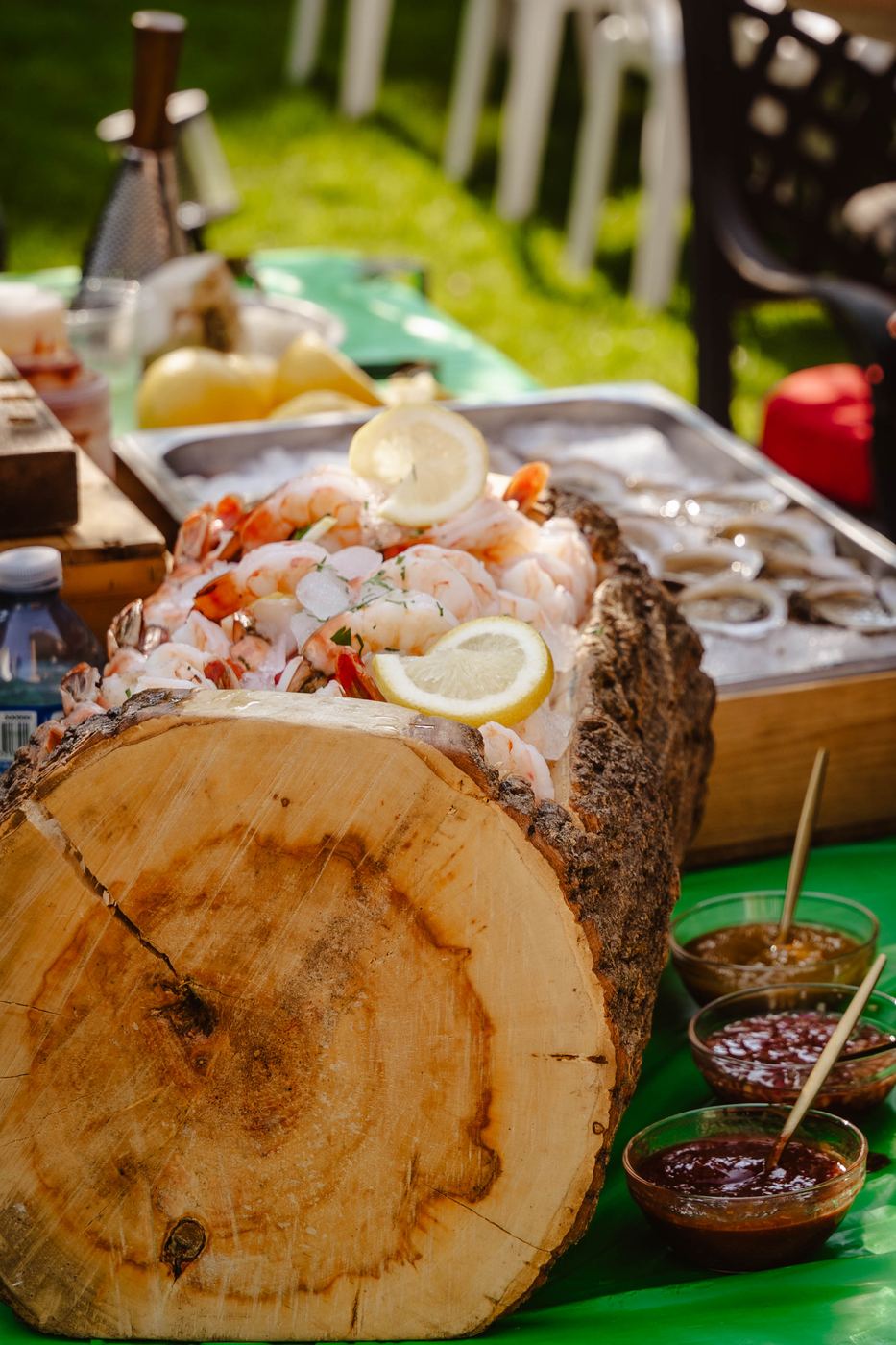 A thick tree-trunk slice used as a shrimp and oyster display at a backyard party