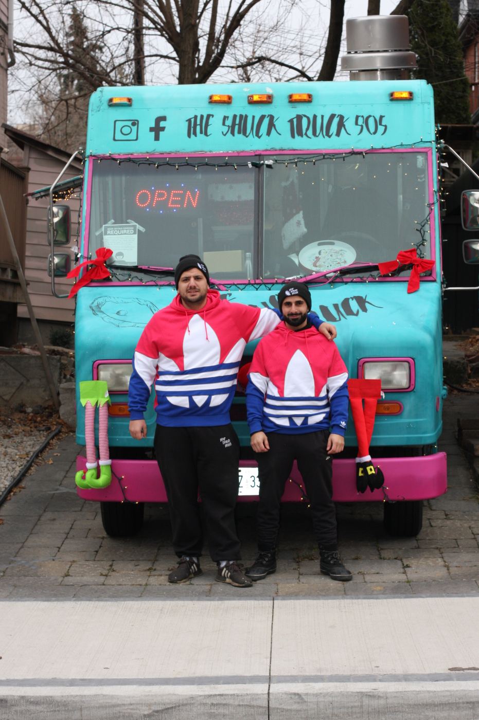 Raffi and Ramsen standing in front of the truck in matching Christmas sweaters