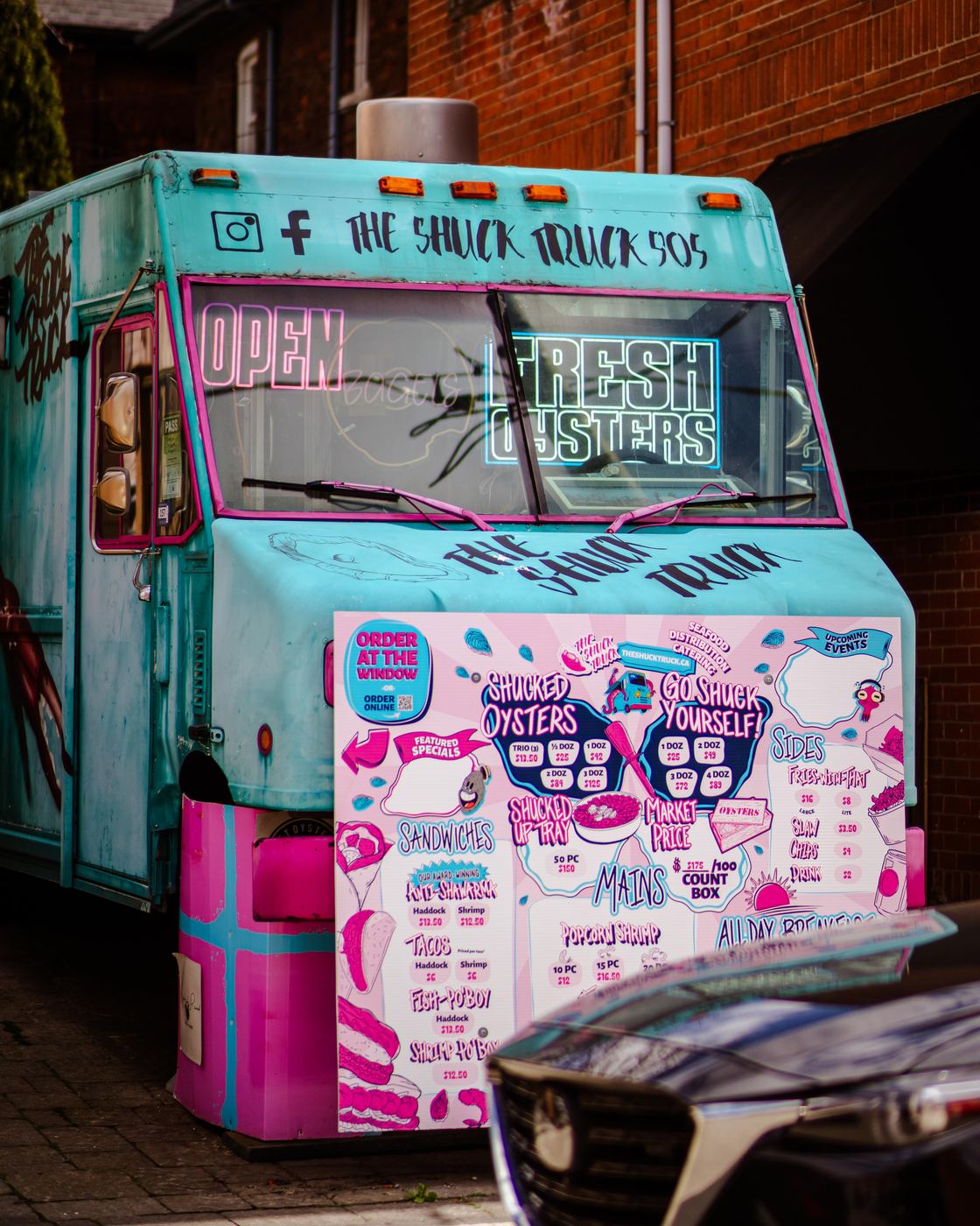 The turquoise and pink Shuck Truck parked on Locke Street with the menu board up