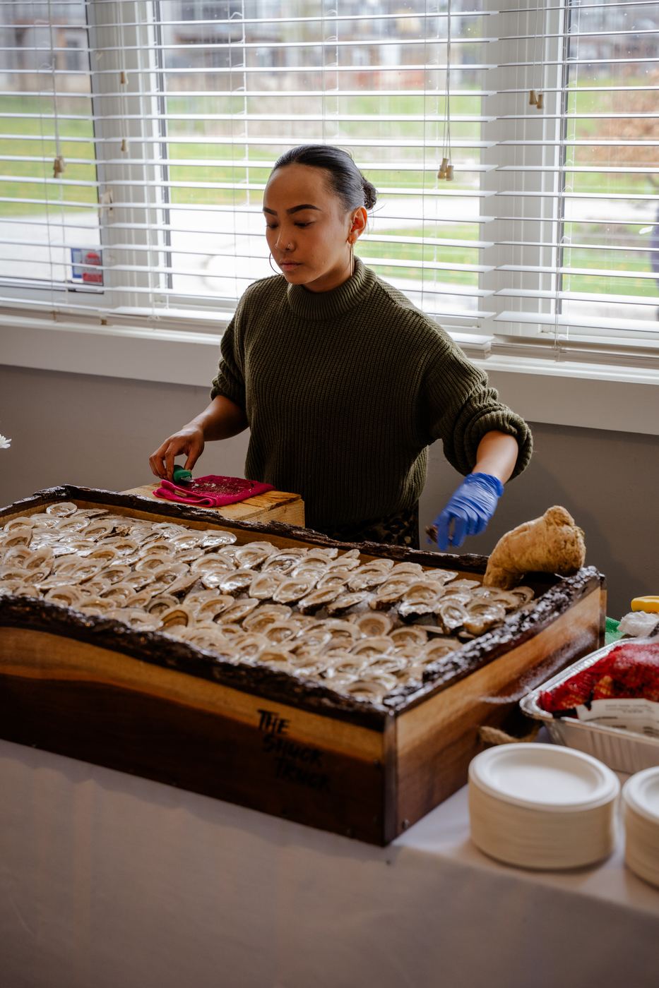 A shucker at the live-edge board by the window, lettered with The Shuck Truck