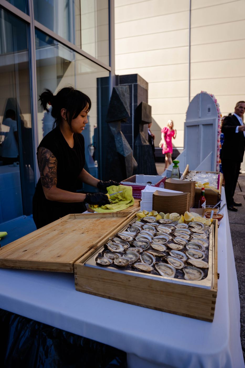 The shucker working behind the wooden tray at a formal outdoor wedding