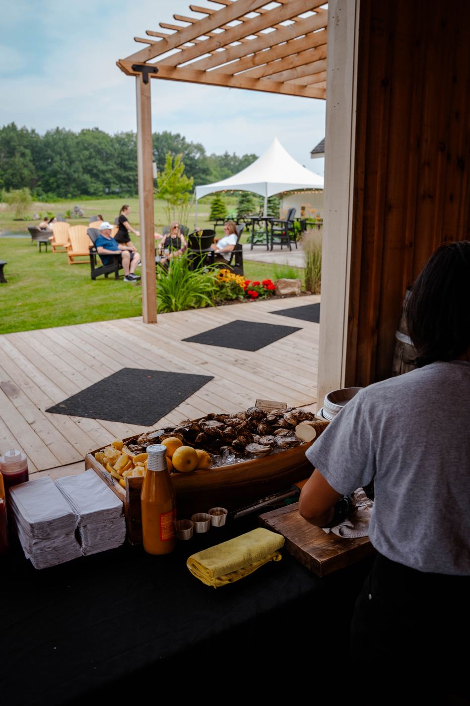 The shucking station set up on a deck under a pergola at a garden wedding
