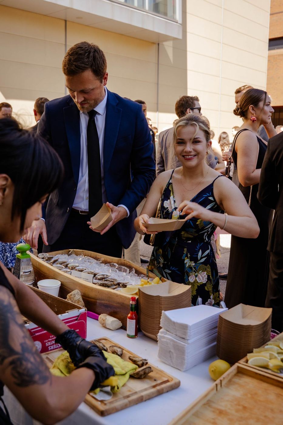 Wedding guests in suits and dresses picking up fresh oysters from the raw bar